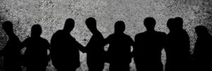 Schatten mehrerer Personen vor grauer Mauer
